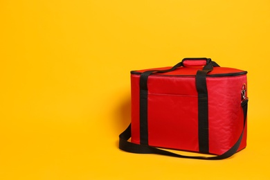 Modern red thermo bag on yellow background. Space for text