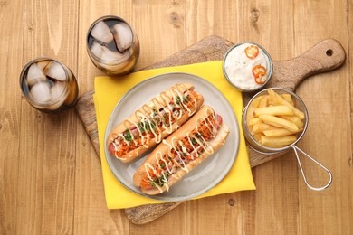 Delicious hot dogs with bacon, carrot and parsley served on wooden table, flat lay