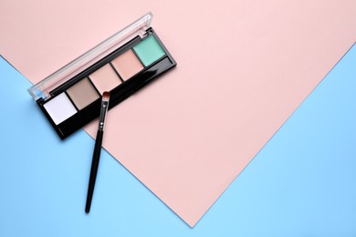 Photo of Contouring palette and brush on color background, flat lay with space for text. Professional cosmetic product