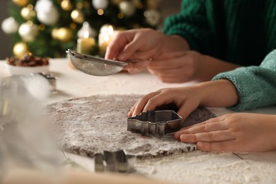 Mother and daughter making Christmas cookies at table together, closeup