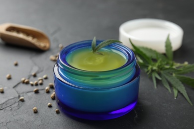 Photo of Jar of hemp cream on dark stone table, closeup. Organic cosmetics