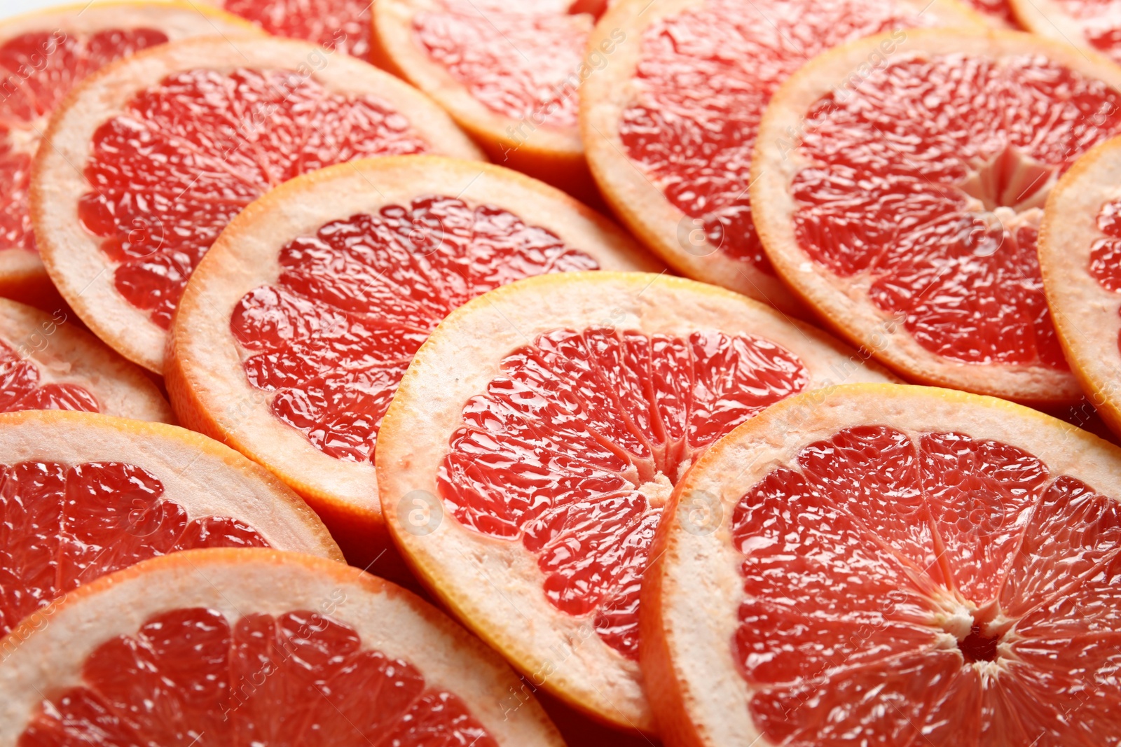 Photo of Many sliced fresh ripe grapefruits as background, closeup