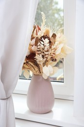 Pink vase with beautiful dried flowers on white windowsill