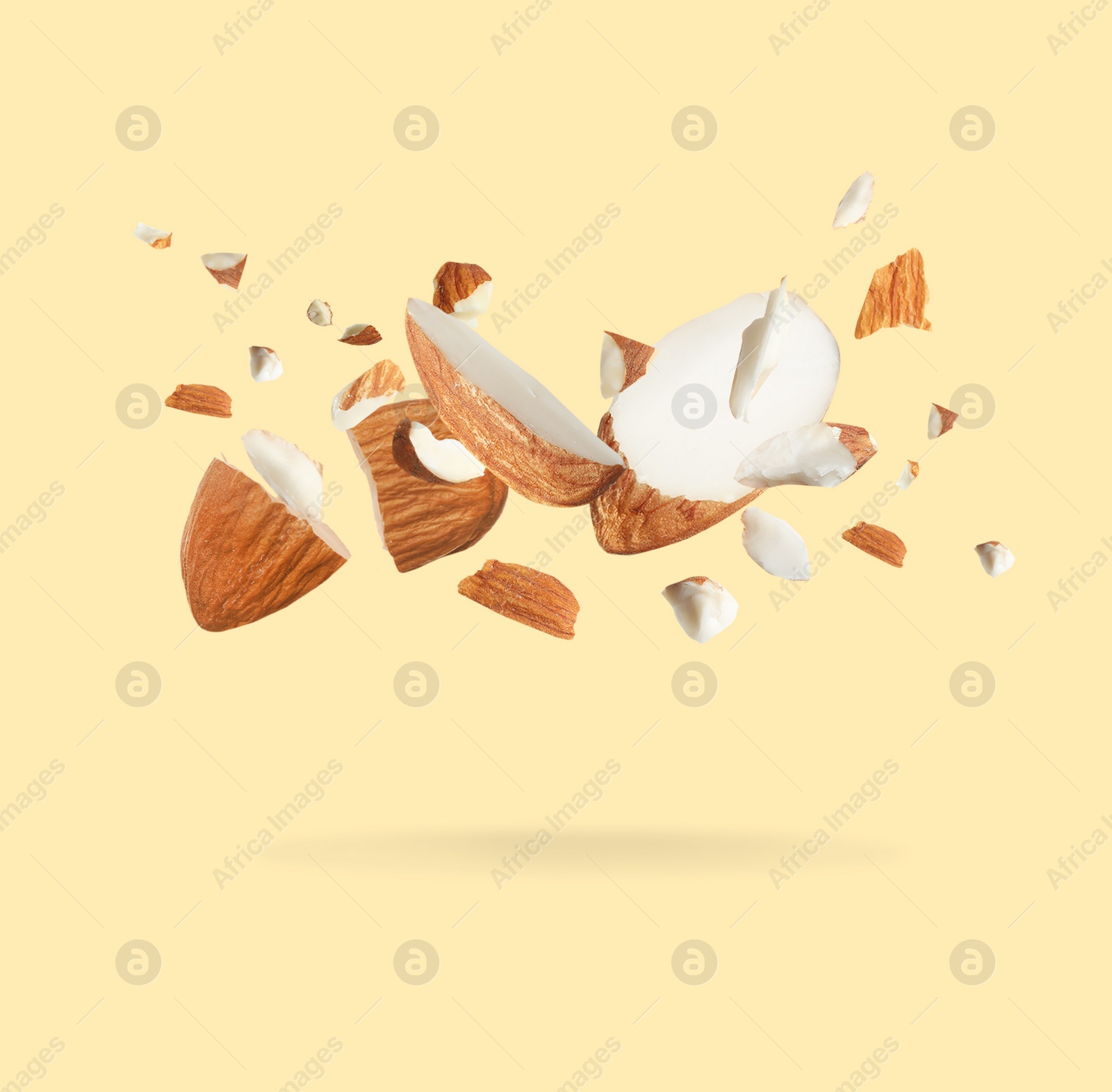 Image of Pieces of tasty almonds falling on beige background