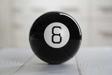 Photo of Magic eight ball on light wooden table, closeup