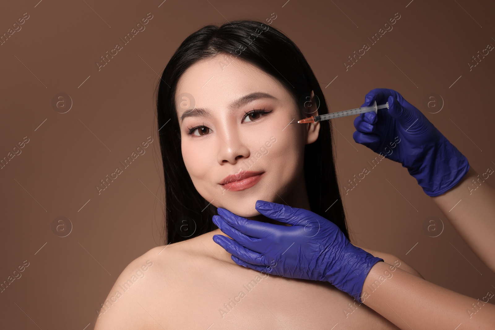 Photo of Woman getting facial injection on brown background