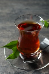 Glass with traditional Turkish tea on grey table