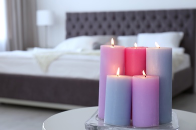 Photo of Burning candles on table in light bedroom