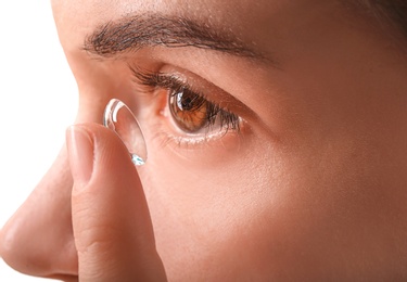 Young woman putting contact lens in her eye, closeup