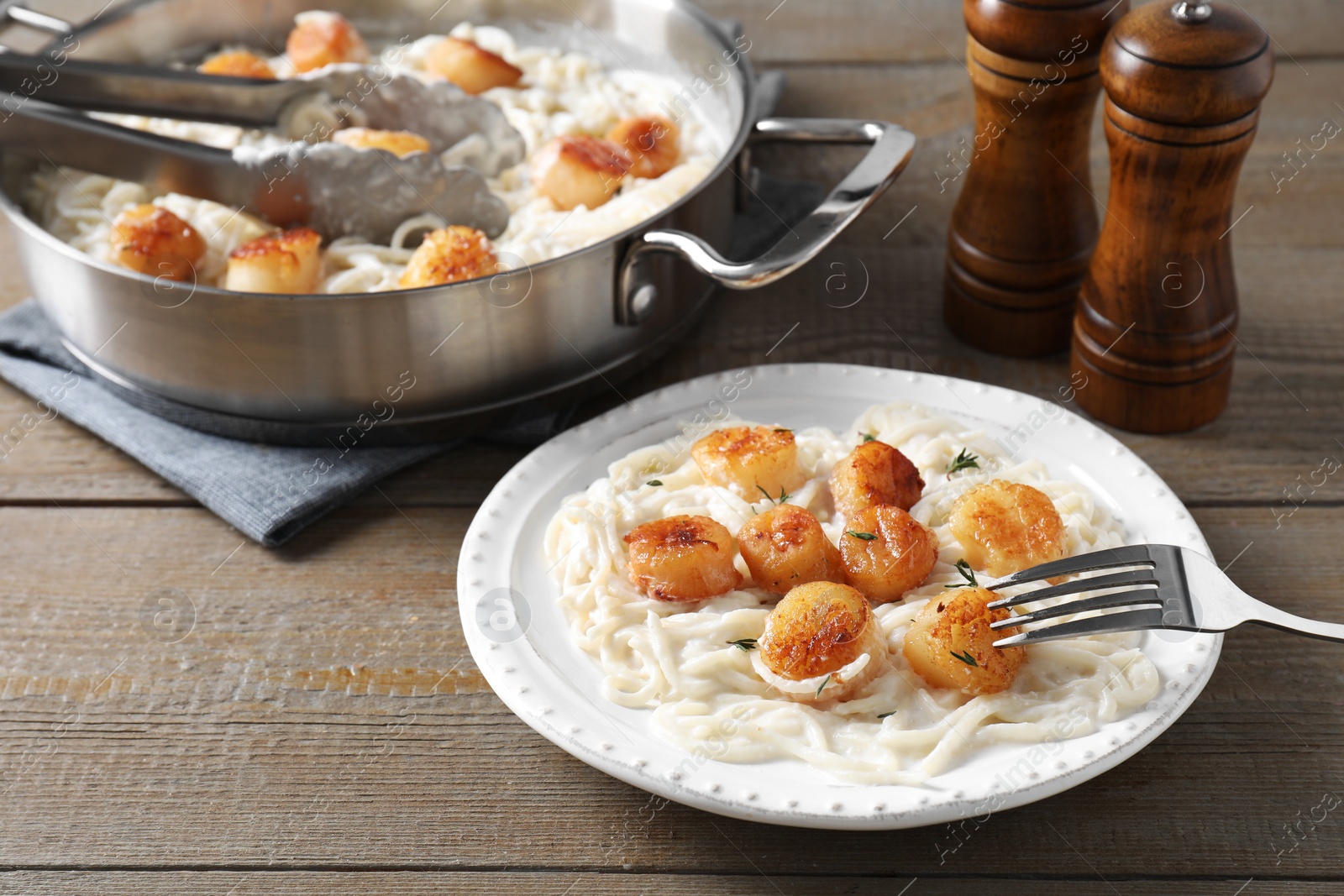 Photo of Delicious scallop pasta served on wooden table