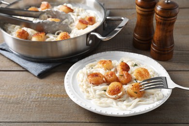 Photo of Delicious scallop pasta served on wooden table