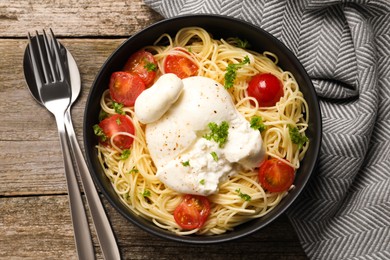 Photo of Delicious spaghetti with burrata cheese and tomatoes on wooden table, flat lay