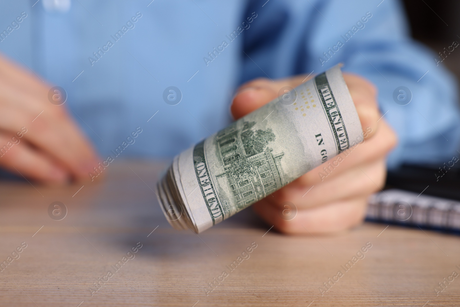 Photo of Money exchange. Woman holding dollar banknotes at wooden table, closeup