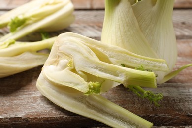 Photo of Whole and cut fennel bulbs on wooden table, closeup