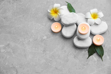 Photo of Composition with spa stones, flowers and candles on grey marble background. Space for text