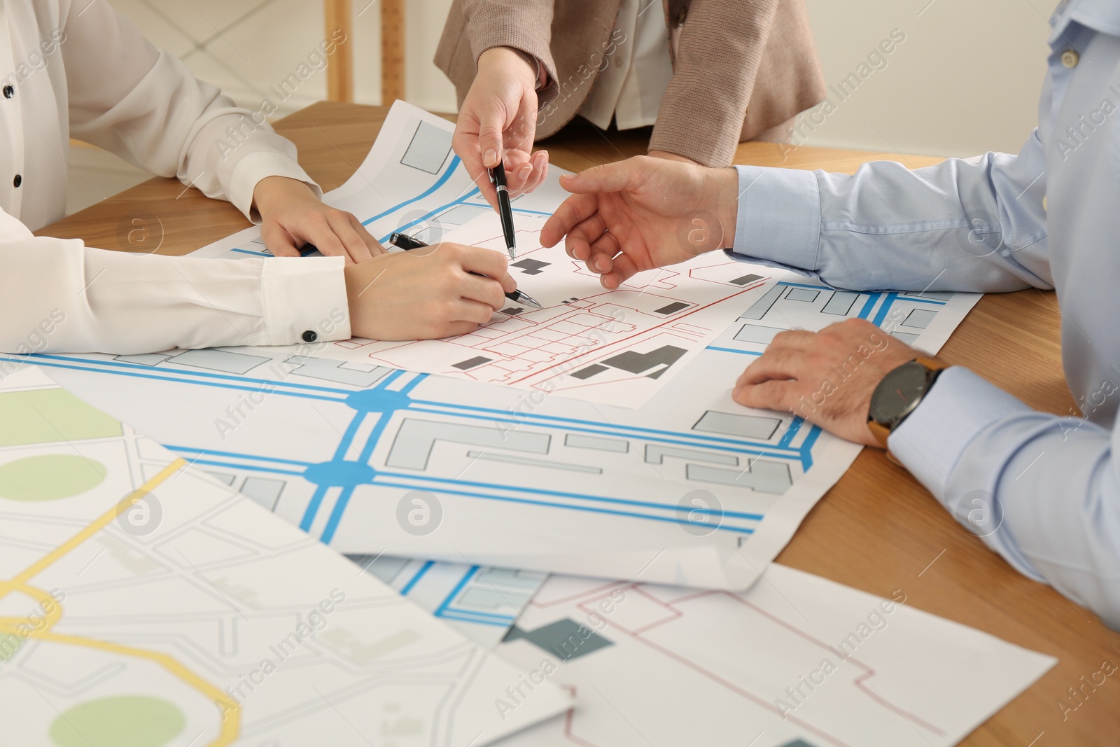 Photo of Professional cartographers working with cadastral map at table, closeup