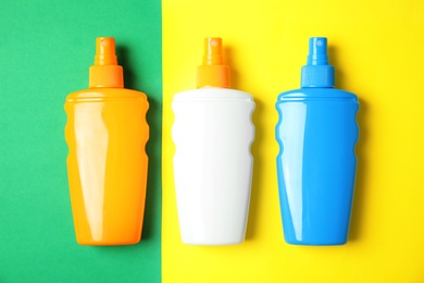 Bottles with sun protection products on color background, top view