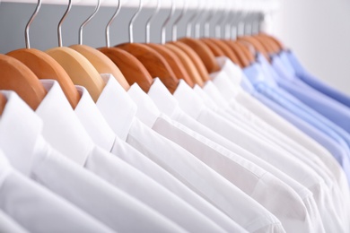 Photo of Clean clothes on hangers after dry-cleaning, closeup