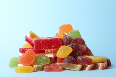 Photo of Pile of delicious bright jelly candies on light blue background