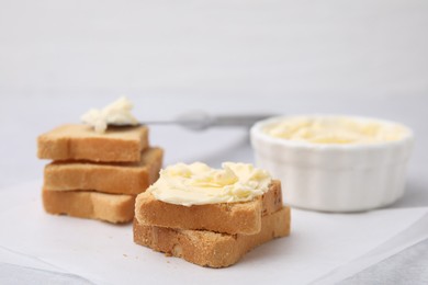 Photo of Slices of bread with tasty butter on light table, closeup