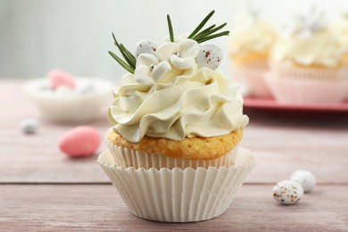 Photo of Tasty Easter cupcake with vanilla cream on wooden table