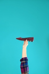 Photo of Young woman holding comfortable shoe on light blue background, closeup