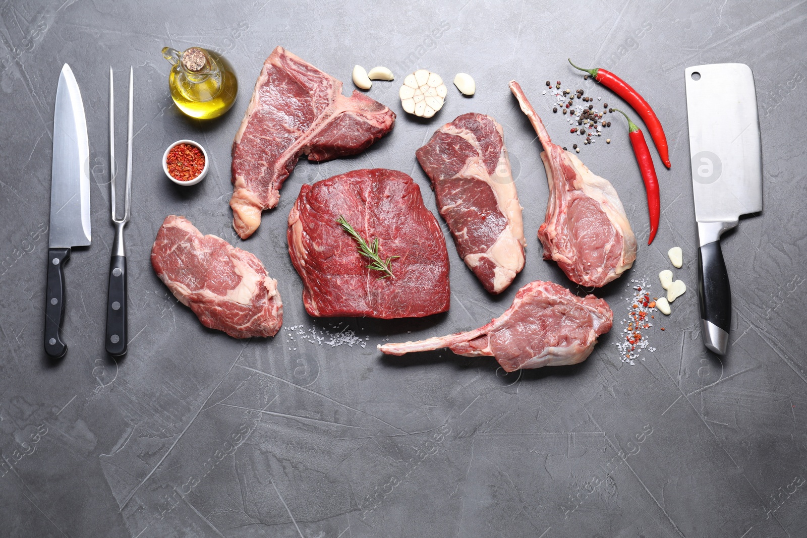 Photo of Fresh raw beef cuts, spices and butcher tools on light grey textured table, flat lay. Space for text