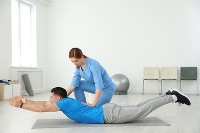 Photo of Professional physiotherapist working with male patient in rehabilitation center