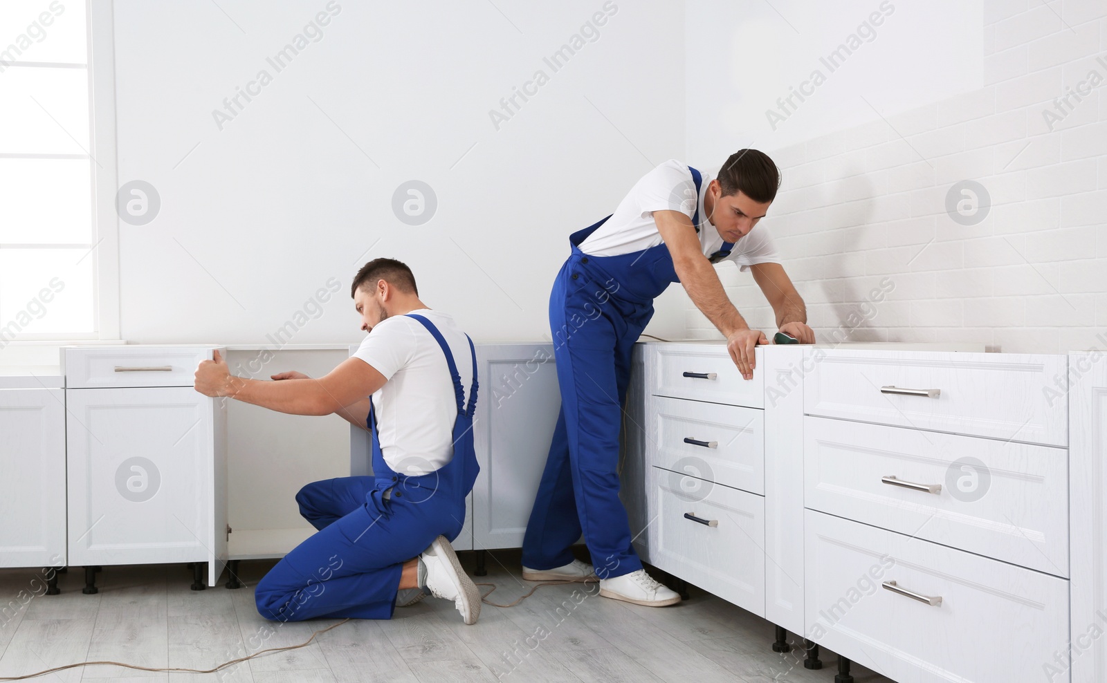 Photo of Maintenance workers installing new kitchen furniture indoors