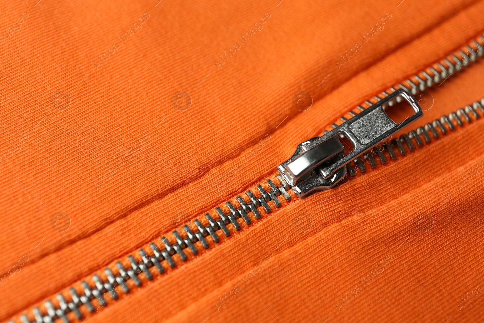 Photo of Orange sweatshirt with zipper as background, closeup view