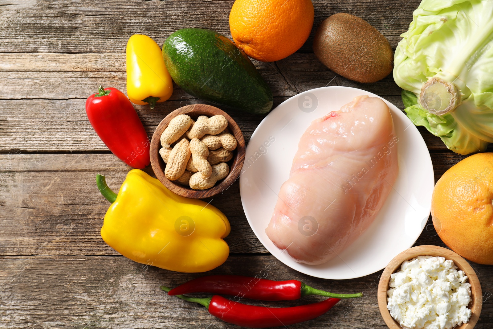 Photo of Healthy meal. Different vegetables and raw chicken breast on wooden table, flat lay