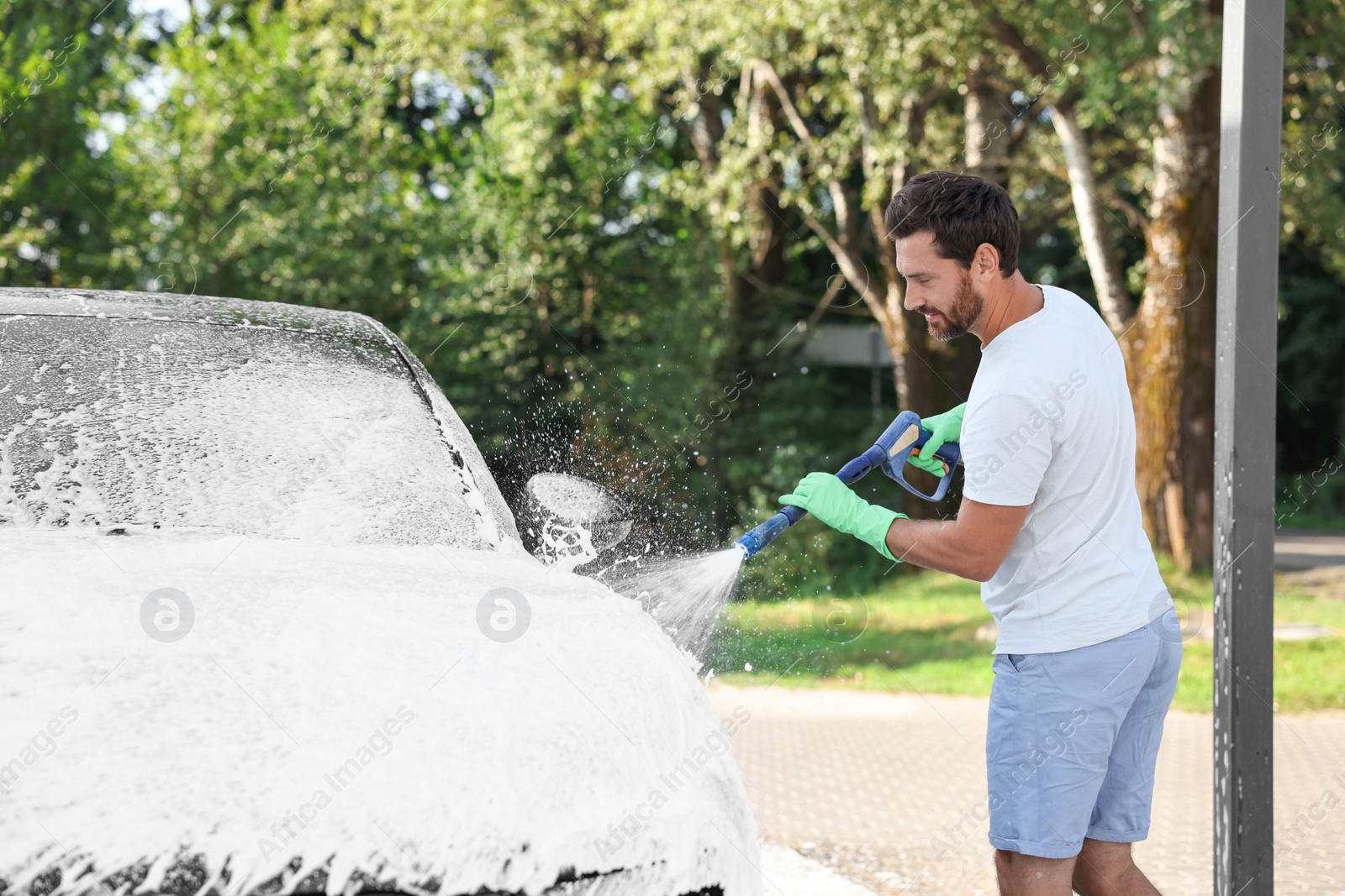 Photo of Man covering automobile with foam at outdoor car wash