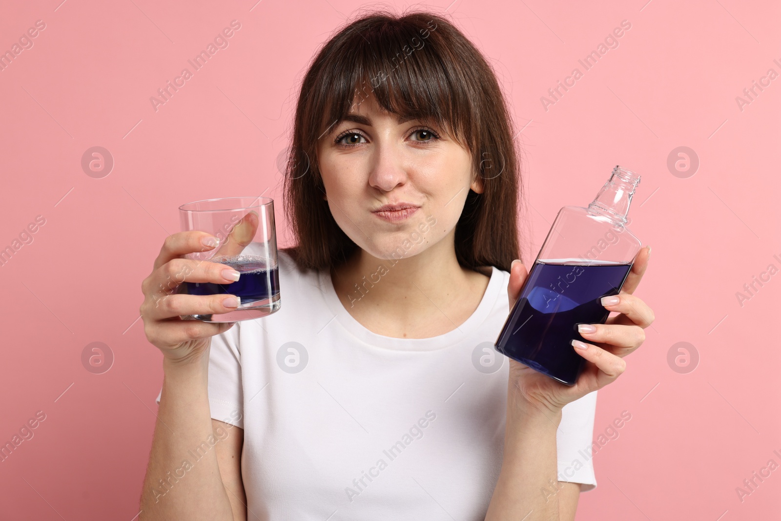 Photo of Young woman using mouthwash on pink background