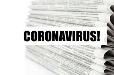 Image of Word CORONAVIRUS and stack of newspapers on white background, closeup. Journalist's work