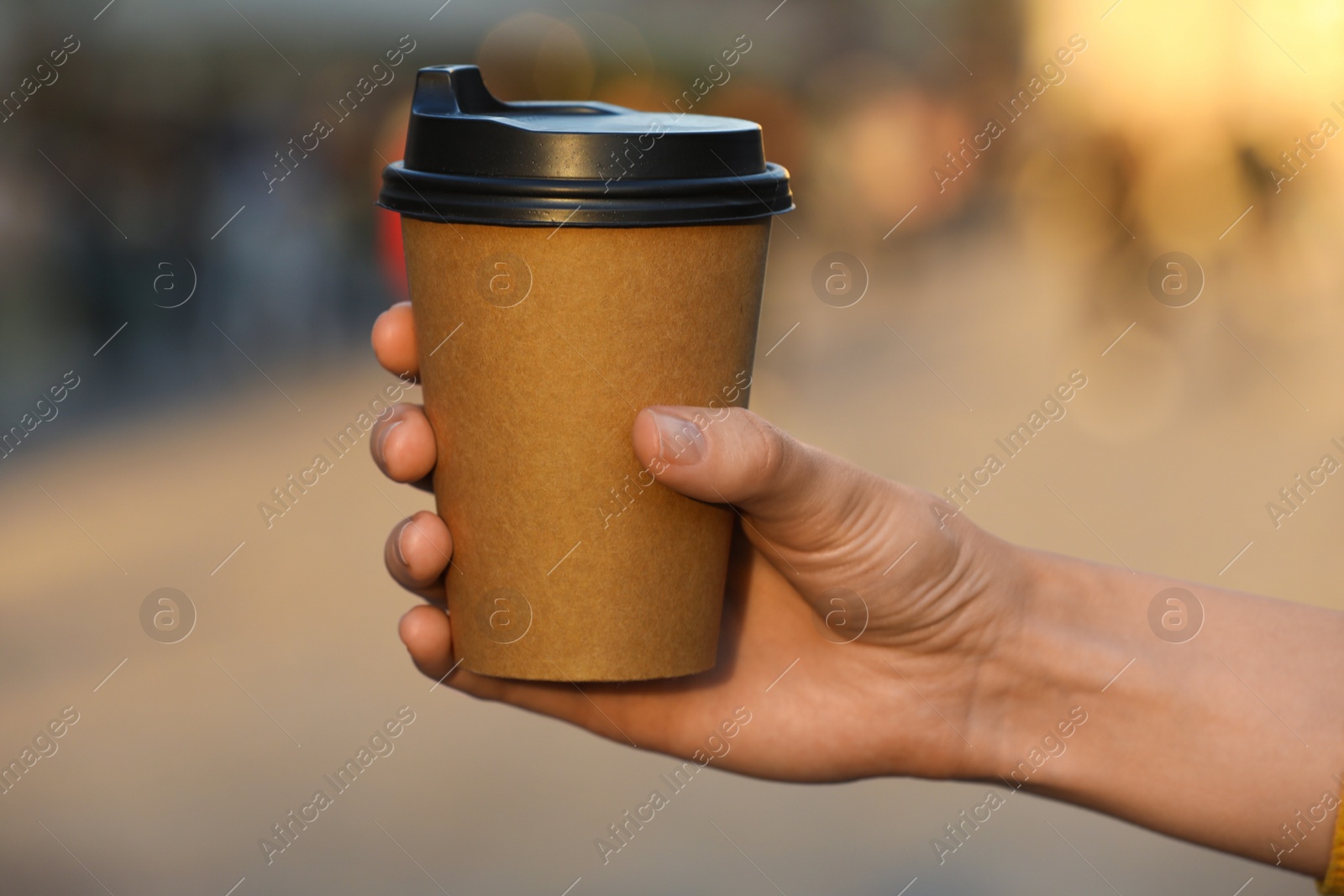 Photo of Woman holding paper takeaway cup outdoors, closeup. Coffee to go