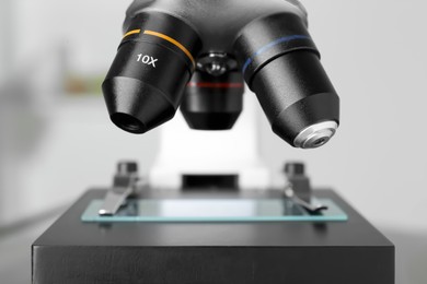 Photo of Modern medical microscope with glass slide on blurred background, closeup