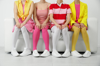 Photo of Women wearing colorful tights sitting on sofa indoors, closeup
