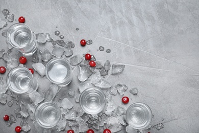 Photo of Shots of vodka, cranberries and ice on grey background, flat lay. Space for text