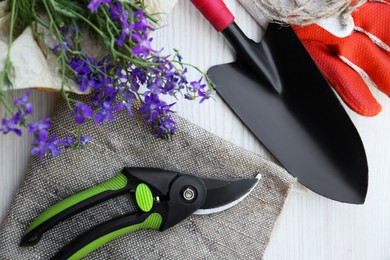 Flat lay composition with secateurs, flowers and other gardening tools on wooden table