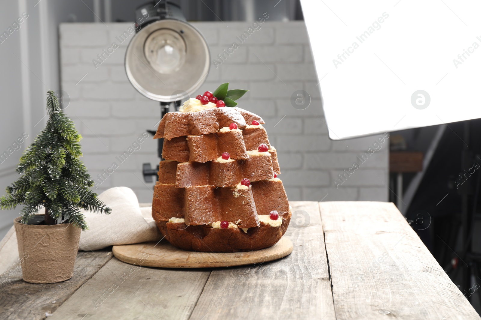 Photo of Professional equipment and Christmas composition with Pandoro cake on wooden table in studio. Food photography