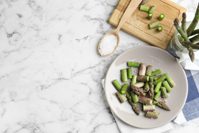Photo of Fresh raw asparagus on white marble table, flat lay. Space for text
