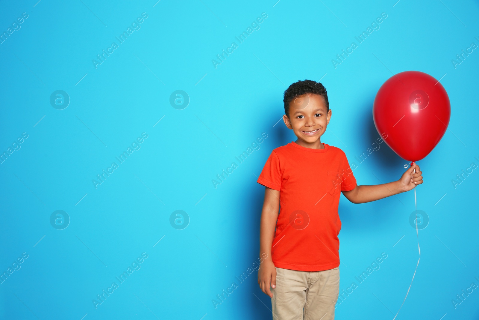 Photo of Cute African-American boy with balloon on color background. Birthday celebration