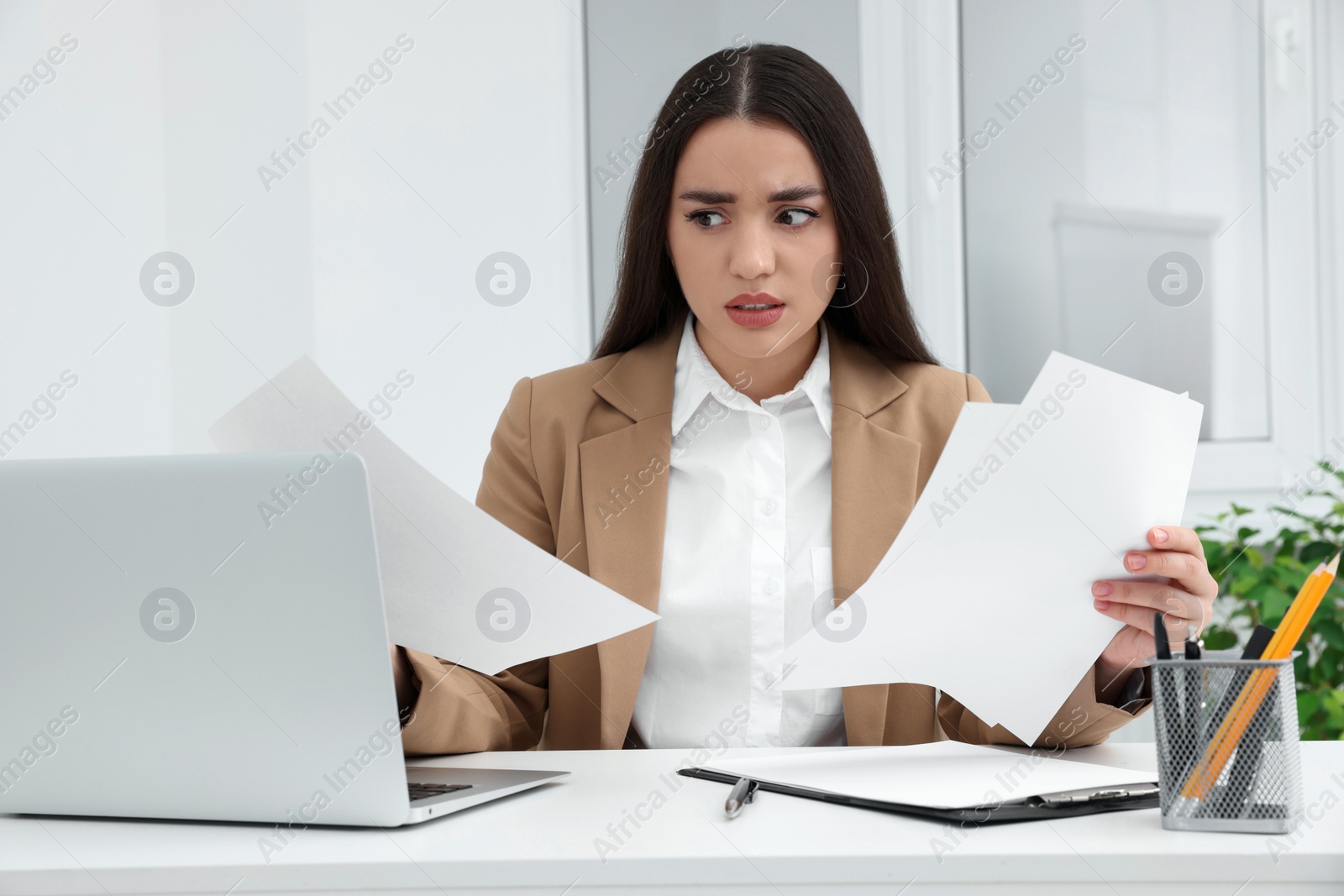 Photo of Unhappy young female intern at table in office