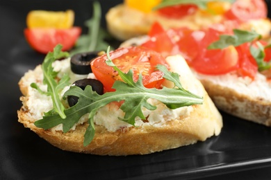 Photo of Delicious tomato bruschetta on black plate, closeup