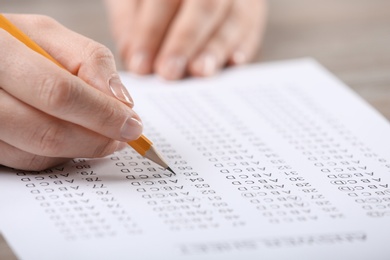 Student filling answer sheet at table, closeup