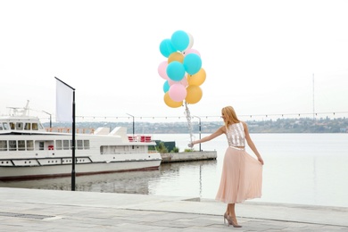 Photo of Beautiful young woman with bunch of balloons outdoors. Space for text