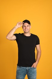 Photo of Happy man in black cap and tshirt on yellow background. Mockup for design