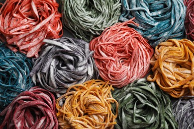 Photo of Rolled pasta painted with food colorings as background, top view