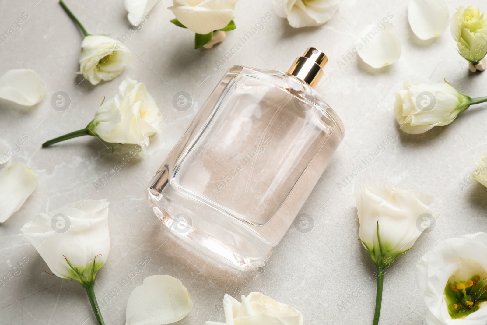 Photo of Composition of bottle with perfume and flowers on light grey marble background