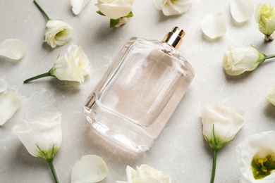 Photo of Composition of bottle with perfume and flowers on light grey marble background